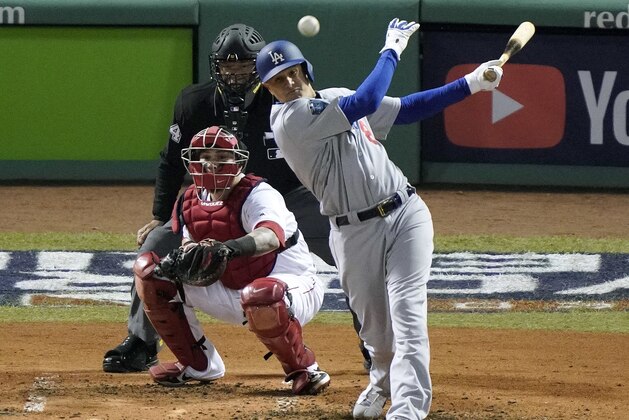 Los Angeles Dodgers' Manny Machado hits a single in front of Boston Red Sox catcher Christian Vazquez during the fourth inning in Game 2 of the World Series baseball game Wednesday, Oct. 24, 2018, in Boston. (AP Photo/Elise Amendola)