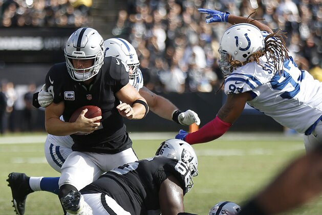 Oakland Raiders quarterback Derek Carr, foreground left, scrambles away from Indianapolis Colts defenders during the second half of an NFL football game in Oakland, Calif., Sunday, Oct. 28, 2018. (AP Photo/D. Ross Cameron)