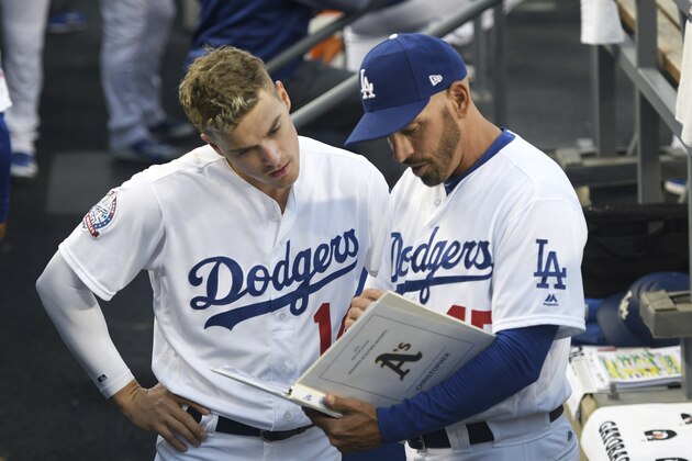 Los Angeles Dodgers' Enrique Hernandez, left, confers with assistant coach Chris Woodward before a baseball game against the Oakland Athletics, Tuesday, April 10, 2018, in Los Angeles. (AP Photo/Michael Owen Baker)