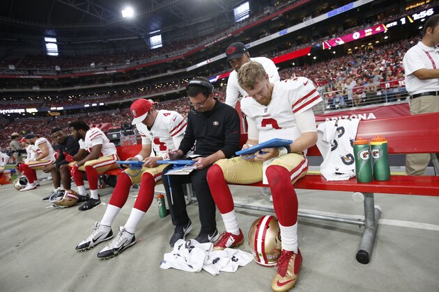 GLENDALE, AZ - OCTOBER 28: Nick Mullens #4, Quarterbacks Coach Rich Scangarello, Tom Savage #12 and C.J. Beathard #3 of the San Francisco 49ers look over plays on the sideline during the game against the Arizona Cardinals at State Farm Stadium on October 28, 2018 in Glendale, Arizona. The Cardinals defeated the 49ers 18-15. (Photo by Michael Zagaris/San Francisco 49ers/Getty Images)