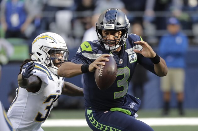 Los Angeles Chargers' Jahleel Addae, left, lunges toward Seattle Seahawks quarterback Russell Wilson before sacking him during the first half of an NFL football game, Sunday, Nov. 4, 2018, in Seattle. (AP Photo/Ted S. Warren)