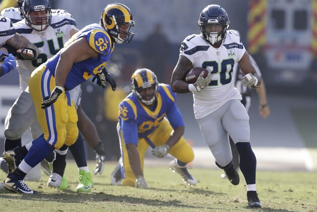 Seattle Seahawks running back Rashaad Penny (20) runs through an opening past Los Angeles Rams nose tackle Ndamukong Suh (93) and defensive tackle Ethan Westbrooks (95), with offensive guard J.R. Sweezy (64) blocking during the first half in an NFL football game Sunday, Nov. 11, 2018, in Los Angeles. (AP Photo/Alex Gallardo)
