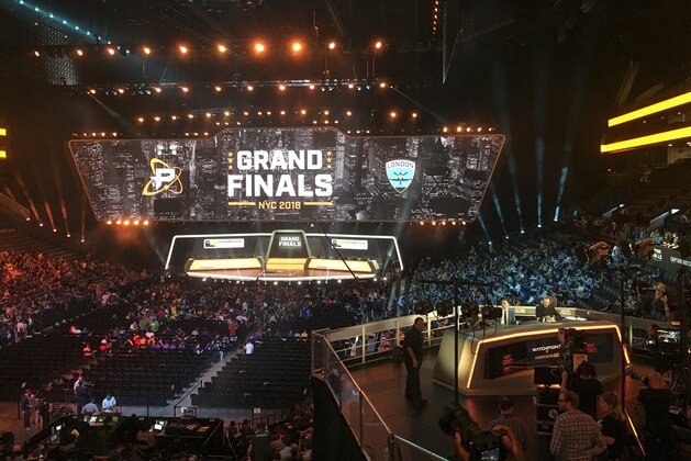 In this Friday, July 27, 2018, fans fill the arena as the stage is set for the Overwatch League Grand Finals' first night of competition, at the Barclays Center in the Brooklyn borough of New York. The Overwatch League is making a grand gamble: that its deep pockets and massive infrastructure can keep it atop the esports mountain even as Fortnite comes charging for the crown. (AP Photo/Terrin Waack)