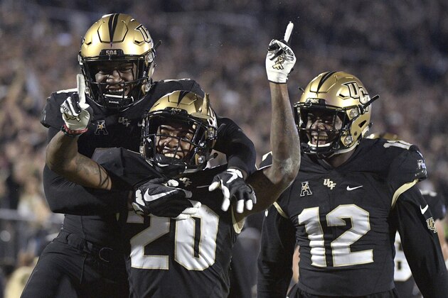 Central Florida defensive back Brandon Moore (20) is congratulated by linebacker Nate Evans, left, and linebacker Eric Mitchell after returning a blocked punt for 60 yards during the first half of an NCAA college football game against Cincinnati Saturday, Nov. 17, 2018, in Orlando, Fla. (AP Photo/Phelan M. Ebenhack)