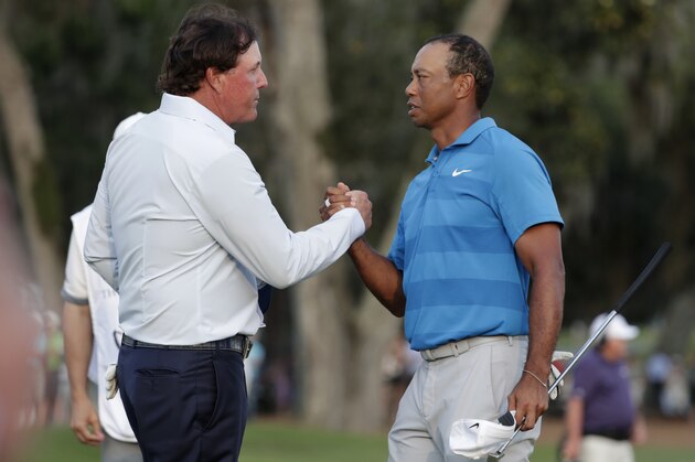 FILE - In this May 10, 2018, file photo, Phil Mickelson, left, and Tiger Woods shake hands after the first round of the Players Championship golf tournament, in Ponte Vedra Beach, Fla.  The winner-take-all match between Tiger Woods and Phil Mickelson is on.  WarnerMedia says it has secured the rights for a pay-per-view event it is promoting as
