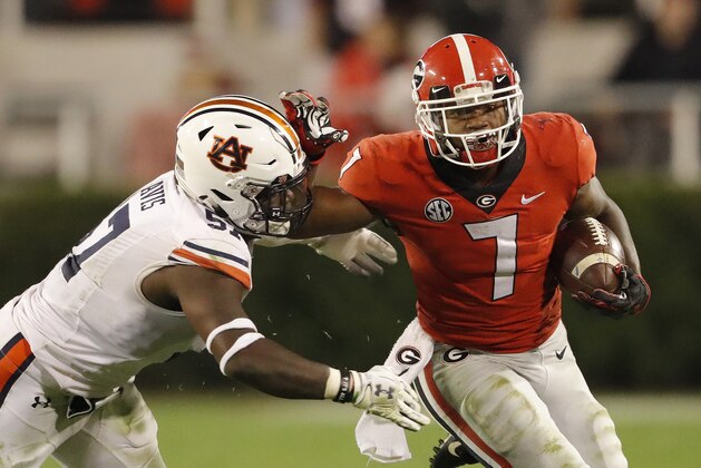 FILE - In this  Saturday, Nov. 10, 2018 file photo, Georgia running back D'Andre Swift (7) fends off Auburn linebacker Deshaun Davis (57) during the second half of an NCAA college football game in Athens, Ga. In Mark Whipple’s two stints as the UMass coach covering 11 years and time spent in FCS and FBS, No. 5 Georgia is his pick as the Minutemen’s toughest opponent. Such playmakers as quarterback Jake Fromm and tailback D’Andre Swift make the Bulldogs heavy favorites on Saturday, Nov. 17, 2018. (AP Photo/John Bazemore, File)