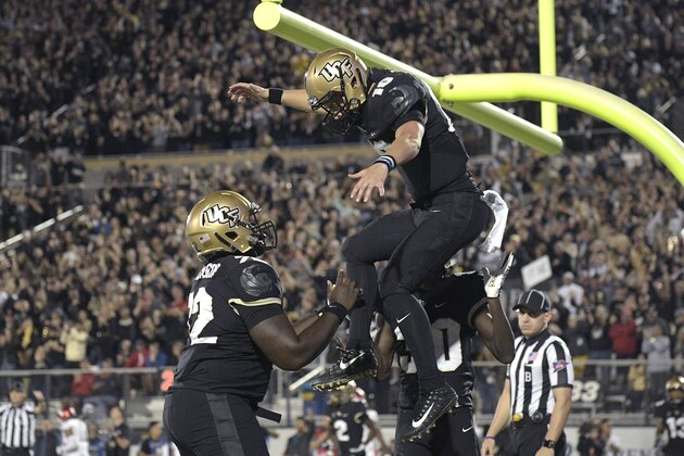 Central Florida quarterback McKenzie Milton (10) celebrates with offensive lineman Jordan Johnson (72) and running back Greg McCrae (30) after Milton rushed for a 3-yard touchdown during the first half of an NCAA college football game against Cincinnati Saturday, Nov. 17, 2018, in Orlando, Fla. (AP Photo/Phelan M. Ebenhack)