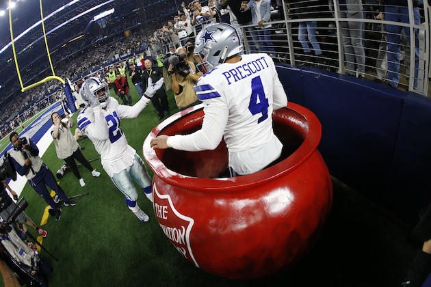 Dak Prescott, de los Cowboys de Dallas, festeja luego de ser llevado a una tetera gigante del Ejército de Salvación por su compañero Ezekiel Elliott, en el partido del jueves 22 de noviembre de 2018, ante los Redskins de Washington (AP Foto/Ron Jenkins)