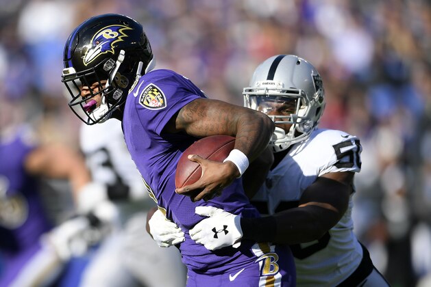 Baltimore Ravens quarterback Lamar Jackson, left, tries to break free from Oakland Raiders linebacker Nicholas Morrow in the first half of an NFL football game, Sunday, Nov. 25, 2018, in Baltimore. (AP Photo/Nick Wass)