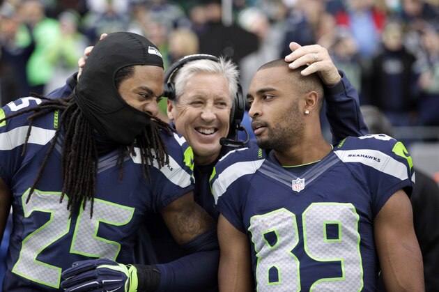 Seattle Seahawks head coach Pete Carroll, center, throws his arms around Richard Sherman (25) and Doug Baldwin before an NFL football game against the Arizona Cardinals, Sunday, Nov. 23, 2014, in Seattle. (AP Photo/Elaine Thompson)