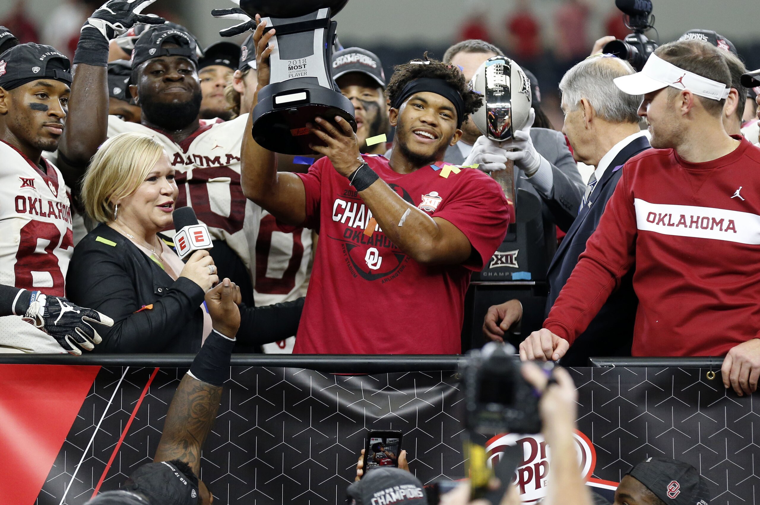 Oklahoma Sooners quarterback Kyler Murray (center) holds up the MVP trophy alongside head coach Lincoln Riley (right) and Holly Rowe (left) after the NCAA Big 12 Conference football championship against the Texas Longhorns, Saturday, Dec. 1, 2018, in Arlington, Texas. Oklahoma beat Texas 39-27. (AP Photo/Roger Steinman)