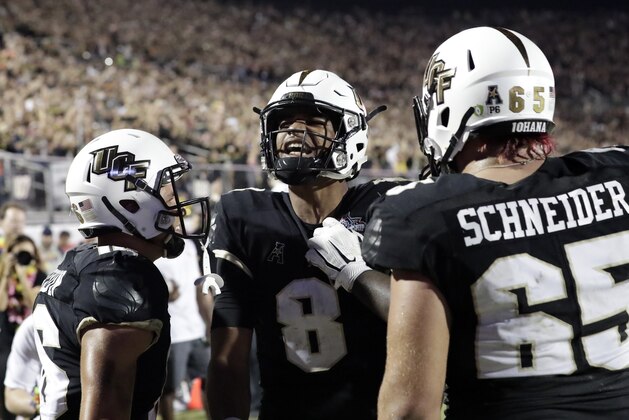 Central Florida quarterback Darriel Mack Jr. (8) celebrates with teammates including offensive lineman Cole Schneider (65) after scoring the go ahead touchdown against Memphis during the second half of the American Athletic Conference championship NCAA college football game, Saturday, Dec. 1, 2018, in Orlando, Fla. (AP Photo/John Raoux)