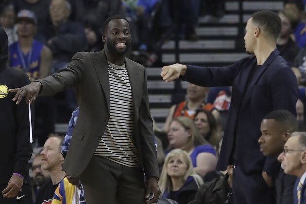 Golden State Warriors forward Draymond Green, left, and guard Stephen Curry gesture from the sideline during the first half of the team's NBA basketball game against the Oklahoma City Thunder in Oakland, Calif., Wednesday, Nov. 21, 2018. (AP Photo/Jeff Chiu)