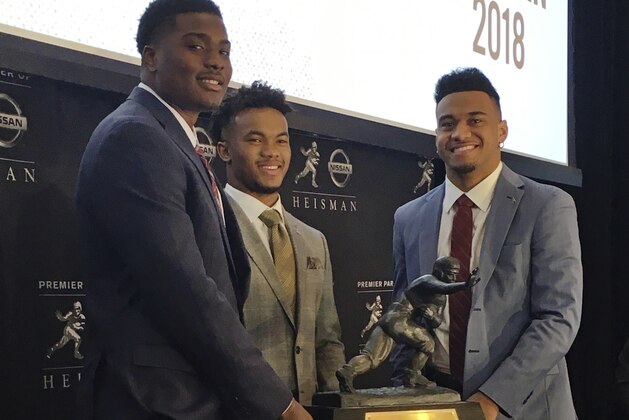 Heisman Trophy finalists, from left, Dwayne Haskins, from Ohio State, Kyler Murray, of Oklahoma, and Tua Tagovailoa, from Alabama, pose with the Heisman Trophy at the New York Stock Exchange, Friday, Dec. 7, 2018, in New York. (AP Photo/Ralph Russo)