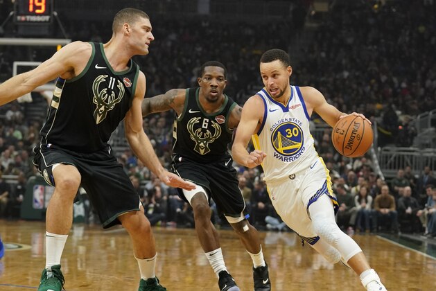 Golden State Warriors' Stephen Curry drives past Milwaukee Bucks' Eric Bledsoe and Brook Lopez during the first half of an NBA basketball game Friday, Dec. 7, 2018, in Milwaukee. (AP Photo/Morry Gash)