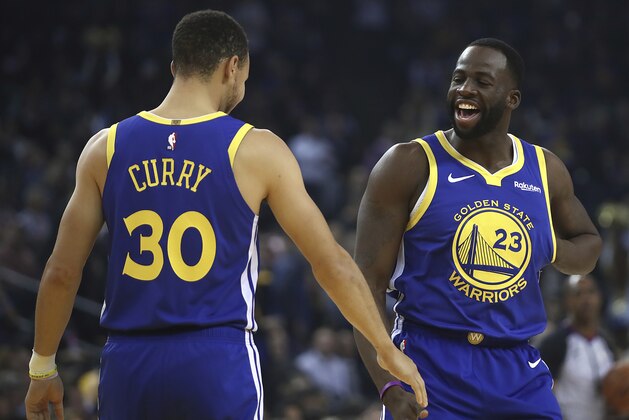 Golden State Warriors' Draymond Green, right, greets Stephen Curry (30) prior to the first half of an NBA basketball game against the Minnesota Timberwolves Monday, Dec. 10, 2018, in Oakland, Calif. The first game both have retuned to play at home since recovering from injuries. (AP Photo/Ben Margot)