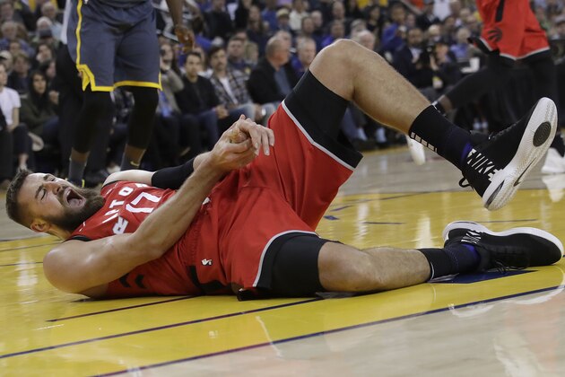 Toronto Raptors center Jonas Valanciunas reacts after injuring his hand during the first half of an NBA basketball game against the Golden State Warriors in Oakland, Calif., Wednesday, Dec. 12, 2018. (AP Photo/Jeff Chiu)