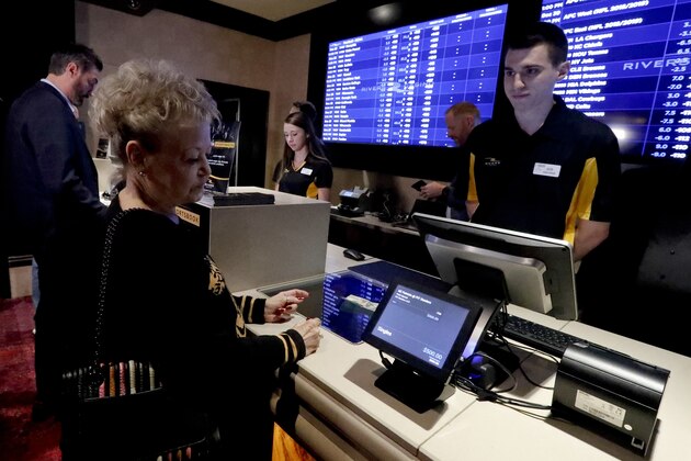 Sheila Kelly, left, looks over her wager as she joins in with the first group of patrons to Rivers Casino to bet on sports as the new, temporary sports betting area opens on Thursday, Dec. 13, 2018, in Pittsburgh. Pending Pennsylvania Gaming Control Board approval, regular operations are scheduled to begin Saturday, Dec. 15. (AP Photo/Keith Srakocic)