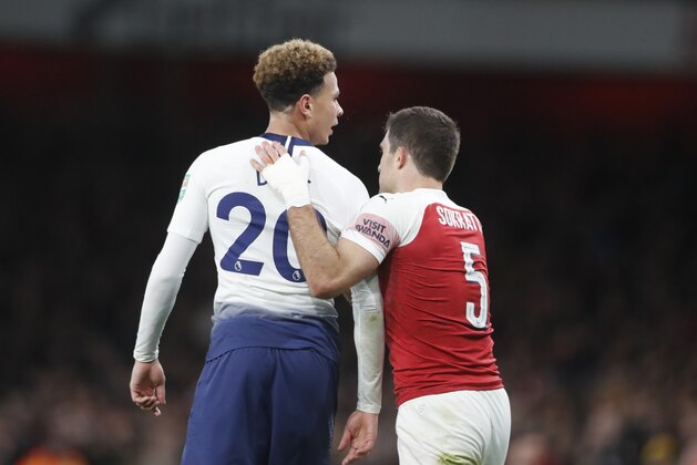 Tottenham's Dele Alli, left, reacts after a bottle was thrown at him from the stands during the English League Cup quarter final soccer match between Arsenal and Tottenham Hotspur at the Emirates stadium in London, Wednesday, Dec. 19, 2018. (AP Photo/Frank Augstein)