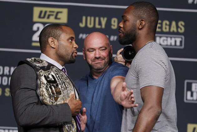 FILE - In this July 6, 2016, file photo, Dana White, center, stands between Daniel Cormier, left, and Jon Jones during a UFC 200 mixed martial arts news conference, in Las Vegas. Daniel Cormier still fights in the shadow of disgraced ex-champion Jon Jones. Cormier defends the UFC light heavyweight championship Saturday, Jan. 20, 2018, in UFC 220 against Volkan Oezdemir. But Cormier must still answer to the fact he has never defeated Jones.  (AP Photo/John Locher, File)