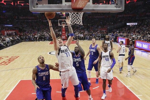 Dallas Mavericks forward Luka Doncic (77) shoots past Los Angeles Clippers' Avery Bradley (11) and Montrezl Harrell (5) during the first half of an NBA basketball game Thursday, Dec. 20, 2018, in Los Angeles. (AP Photo/Marcio Jose Sanchez)