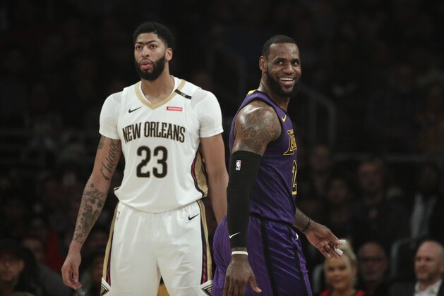 Los Angeles Lakers' LeBron James, right, smiles as he walks past New Orleans Pelicans' Anthony Davis during the first half of an NBA basketball game Friday, Dec. 21, 2018, in Los Angeles. (AP Photo/Jae C. Hong)