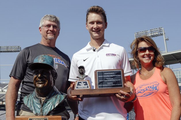 Florida pitcher Brady Singer poses with his parents, Brett and Jacquelyn Singer, while holding the Dick Howser Trophy for college baseball's player of the year, in Omaha, Neb., Friday, June 15, 2018. Singer carries a 12-1 record and 2.30 ERA into the College World Series. The native of Eustis, Florida, was the No. 18 overall pick in the baseball draft by the Kansas City Royals. (AP Photo/Nati Harnik)