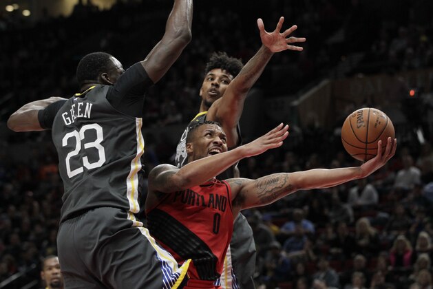 Portland Trail Blazers guard Damian Lillard, center, drives to the basket against Golden State Warriors forward Draymond Green, left, and guard Nick Young during the second half of an NBA basketball game in Portland, Ore., Wednesday, Feb. 14, 2018. The Trail Blazers won 123-117. (AP Photo/Steve Dipaola)