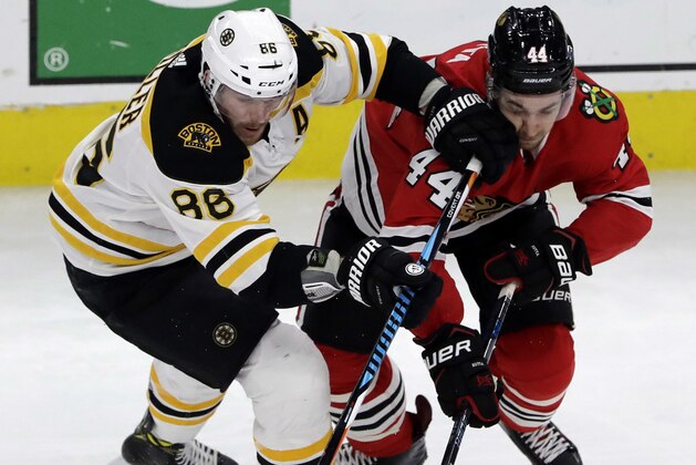 Boston Bruins defenseman Kevan Miller, left, and Chicago Blackhawks defenseman Jan Rutta battle for the puck during the first period of an NHL hockey game Sunday, March 11, 2018, in Chicago. (AP Photo/Nam Y. Huh)