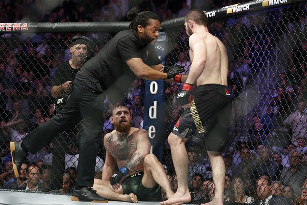 Khabib Nurmagomedov, right, is held back by referee Herb Dean after fighting Conor McGregor, bottom, during a lightweight title mixed martial arts bout at UFC 229 in Las Vegas, Saturday, Oct. 6, 2018. Nurmagomedov won the fight by submission during the fourth round to retain the title. (AP Photo/John Locher)