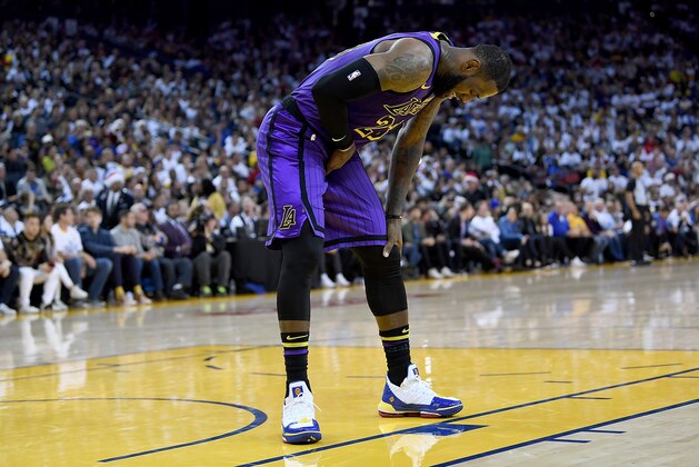OAKLAND, CA - DECEMBER 25:  LeBron James #23 of the Los Angeles Lakers leans over in pain after he was hurt against the Golden State Warriors during the second half of their NBA Basketball game at ORACLE Arena on December 25, 2018 in Oakland, California. NOTE TO USER: User expressly acknowledges and agrees that, by downloading and or using this photograph, User is consenting to the terms and conditions of the Getty Images License Agreement.  (Photo by Thearon W. Henderson/Getty Images)