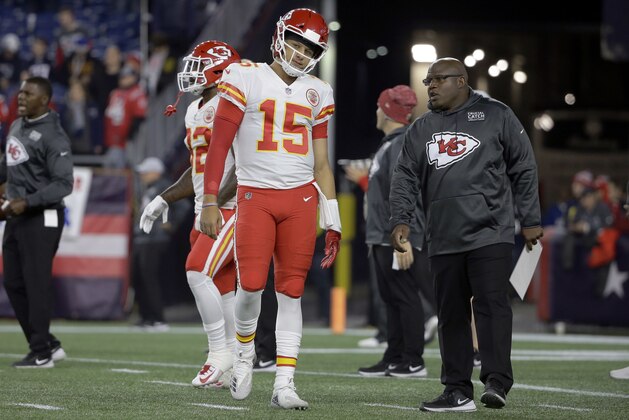 Kansas City Chiefs quarterback Patrick Mahomes listens to offensive coordinator Eric Bieniemy, right, as he warms up before an NFL football game against the New England Patriots, Sunday, Oct. 14, 2018, in Foxborough, Mass. (AP Photo/Steven Senne)