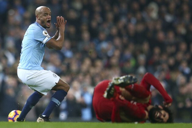 Manchester City's Vincent Kompany, left, reacts as Liverpool's Mohamed Salah lies on the pitch during the English Premier League soccer match between Manchester City and Liverpool at the Etihad Stadium in Manchester, England, Thursday, Jan. 3, 2019.(AP Photo/Dave Thompson)