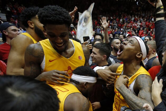 New Mexico guard Keith McGee (3) and forward Corey Manigault, left, celebrate with fans after the team's 85-58 victory over Nevada in an NCAA college basketball game in Albuquerque, N.M., Saturday, Jan. 5, 2019. (AP Photo/Andres Leighton)