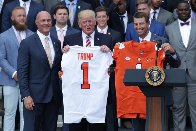 WASHINGTON, DC - JUNE 12:  Clemson University President Jim Clements (L) and Clemson Tigers head coach Dabo Swinney (R) present two jerseys, one for President Donald Trump (2nd L) and one for his son Barron, during a South Lawn event at the White House June 12, 2017 in Washington, DC. President Trump hosted the team to honor 2016 NCAA Football National Championship.  (Photo by Alex Wong/Getty Images)
