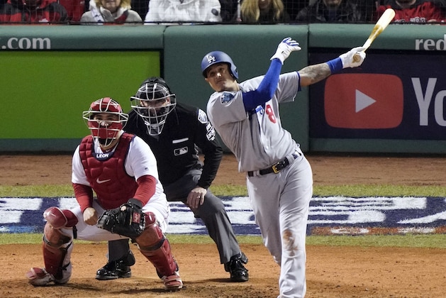 Los Angeles Dodgers' Manny Machado hits a sacrifice fly to drive in Max Muncy during the seventh inning of Game 1 of the World Series baseball game against the Boston Red Sox Tuesday, Oct. 23, 2018, in Boston. (AP Photo/Elise Amendola)