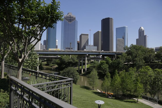 CORRECTS SOURCE OF FUNDING TO A PUBLIC-PRIVATE PARTNERSHIP BETWEEN THE CITY AND THE NONPROFIT ORGANIZATION BUFFALO BAYOU PARTNERSHIP A railing from an apartment complex and the Houston skyline overlook the Buffalo Bayou as it snakes its' way into downtown Friday, April 18, 2014. The city and the nonprofit Buffalo Bayou Partnership are spending $58 million to improve the waterway and the surrounding parks and bike and jogging trails. (AP Photo/Pat Sullivan)
