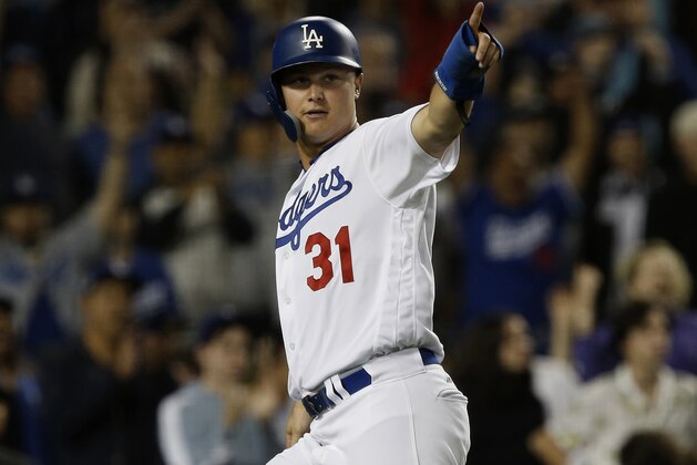 Los Angeles Dodgers' Joc Pederson, points to Yasiel Puig as he scores on a RBI single by Puig against the San Diego Padres during the eighth inning of a baseball game in Los Angeles, Friday, Sept. 21, 2018. (AP Photo/Alex Gallardo)