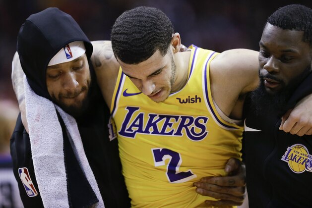 Los Angeles Lakers guard Lonzo Ball, center, is carried off the court by Michael Beasley, left, and Lance Stephenson after Ball sustained an injury during the second half of the team's NBA basketball game against the Houston Rockets, Saturday, Jan. 19, 2019, in Houston. (AP Photo/Eric Christian Smith)