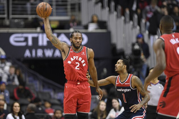 Toronto Raptors forward Kawhi Leonard (2) holds the ball against Washington Wizards forward Trevor Ariza (1) during overtime of an NBA basketball game, Sunday, Jan. 13, 2019, in Washington. The Raptors won 140-138 in double overtime. (AP Photo/Nick Wass)