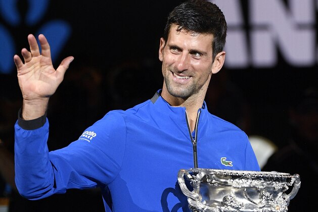 Serbia's Novak Djokovic holds waves as he hold his trophy after defeating Spain's Rafael Nadal in the men's singles final at the Australian Open tennis championships in Melbourne, Australia, Sunday, Jan. 27, 2019. (AP Photo/Andy Brownbill)