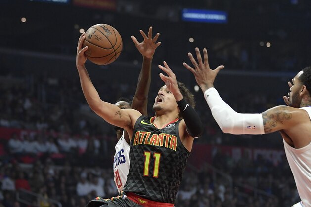 Atlanta Hawks guard Trae Young, center, shoots as Los Angeles Clippers guard Patrick Beverley, left, and forward Mike Scott defend during the first half of an NBA basketball game Monday, Jan. 28, 2019, in Los Angeles. (AP Photo/Mark J. Terrill)