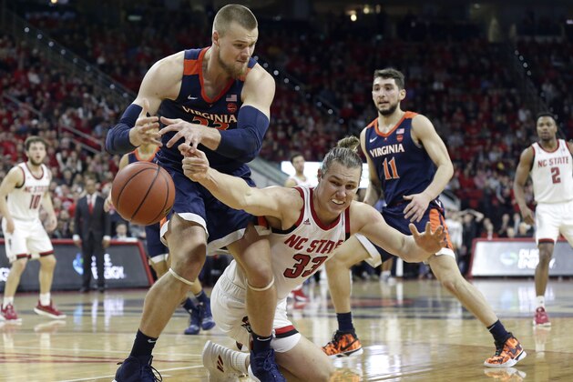 Virginia's Jack Salt, left, and North Carolina State's Wyatt Walker reach for a loose ball during the first half of an NCAA college basketball game in Raleigh, N.C., Tuesday, Jan. 29, 2019. (AP Photo/Gerry Broome)
