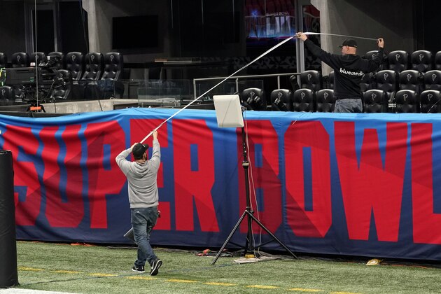 Workers use a tape measure as they hang a sign inside Mercedes-Benz Stadium for the NFL Super Bowl 53 football game Tuesday, Jan. 29, 2019, in Atlanta. (AP Photo/David J. Phillip)