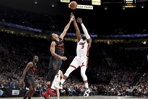 Miami Heat guard Dwyane Wade, right, hits a shot over Portland Trail Blazers guard CJ McCollum, center, as forward Al-Farouq Aminu watches during the first half of an NBA basketball game in Portland, Ore., Tuesday, Feb. 5, 2019. (AP Photo/Steve Dykes)