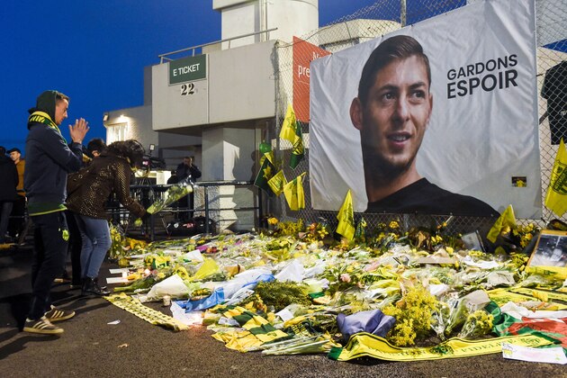 Supporters stand in front of flowers and a giant portrait of Nantes' Argentinian forward Emilianio Sala before the French L1 football match between FC Nantes and AS Saint Etienne (ASSE) at the La Beaujoire stadium in Nantes, western France on January 30, 2019. - A plane transporting Sala -- who had just been transferred from French team Nantes to Premier League club Cardiff City in a 17-million-euro ($19.3-million) move -- and British pilot Dave Ibbotson vanished from radar around 20 kilometres (12 miles) north of the Channel island of Guernsey on January 21. (Photo by SEBASTIEN SALOM GOMIS / AFP)        (Photo credit should read SEBASTIEN SALOM GOMIS/AFP/Getty Images)