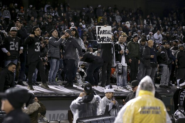 A fan holds up a sign while standing on a dugout at Oakland Alameda County Coliseum after an NFL football game between the Oakland Raiders and the Denver Broncos in Oakland, Calif., Monday, Dec. 24, 2018. (AP Photo/John Hefti)
