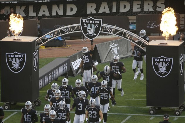 Oakland Raiders linebacker Xavier Woodson-Luster (56) touches the team logo as players run onto the field before an NFL preseason football game against the Seattle Seahawks in Oakland, Calif., Thursday, Aug. 31, 2017. (AP Photo/Jeff Chiu)