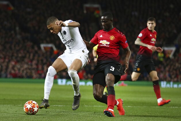Paris Saint Germain's Kylian Mbappe, left, defends the ball as Manchester United's Eric Bailly goes to challenge during the Champions League round of 16 soccer match between Manchester United and Paris Saint Germain at Old Trafford stadium in Manchester, England, Tuesday, Feb. 12,2019.(AP Photo/Dave Thompson)