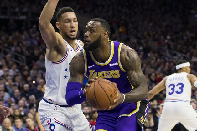 Los Angeles Lakers' LeBron James, right, makes his move against Philadelphia 76ers' Ben Simmons, left, of Australia, during the first half of an NBA basketball game, Sunday, Feb. 10, 2019, in Philadelphia. (AP Photo/Chris Szagola)
